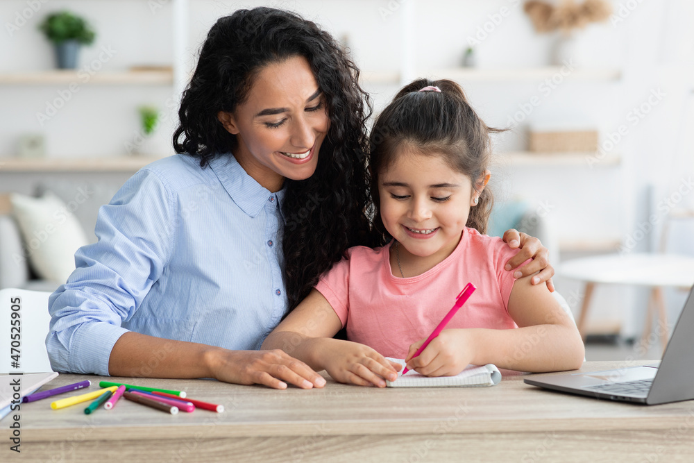 Caring arab mother helping her little daughter with homework and study Caring arab mother helping her little daughter with homework and study