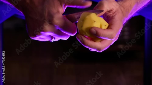 A man cuts a peeled potato in two