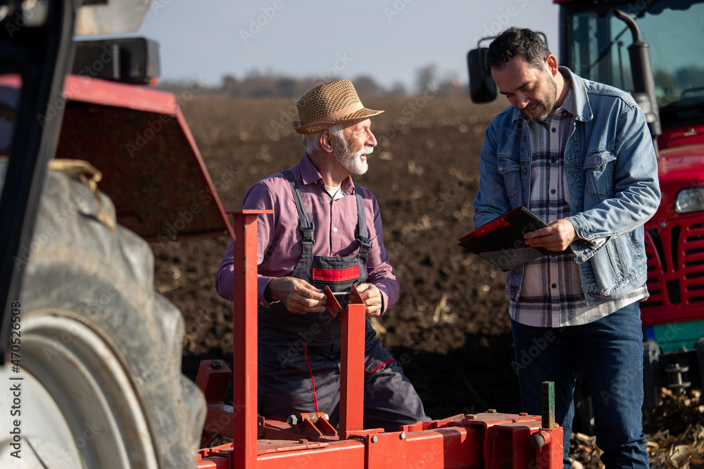 Farmers repairing tractor in field Farmers repairing tractor in field