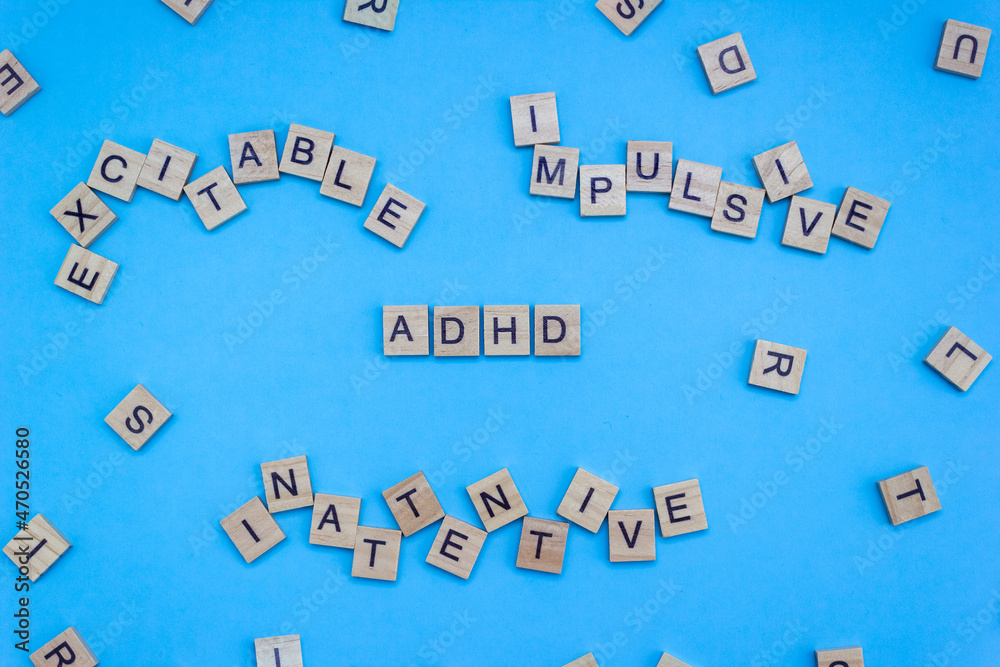 Wooden blocks with lettering ADHD and chaotic letters on a blue background. Minimal concept of attention deficit hyperactivity syndrome. Selective focus - obrazy, fototapety, plakaty 