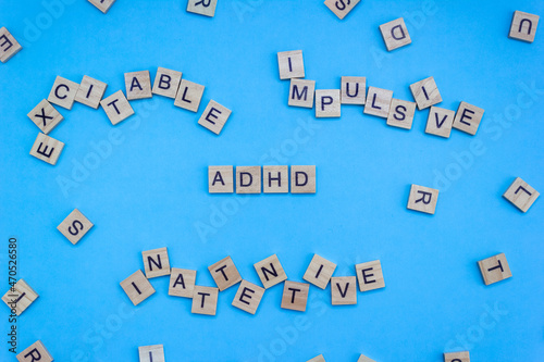 Wooden blocks with lettering ADHD and chaotic letters on a blue background. Minimal concept of attention deficit hyperactivity syndrome. Selective focus photo