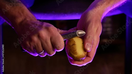 A married man peels potatoes with a vegetable peeler