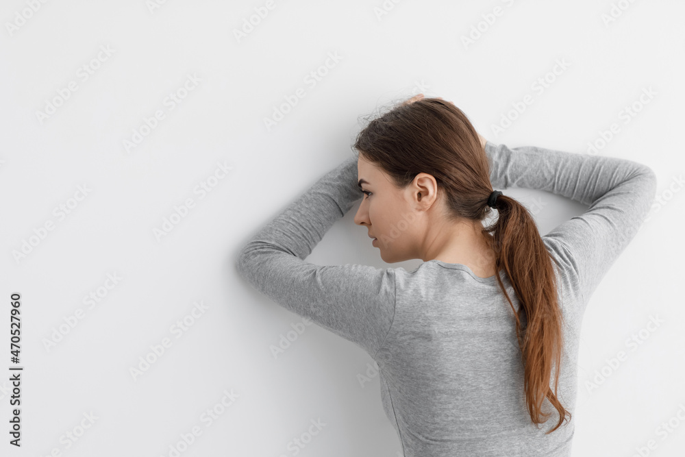 Unhappy worried caucasian millennial lady suffering from depression, leaning against white wall at home Unhappy worried caucasian millennial lady suffering from depression, leaning against white wall at home