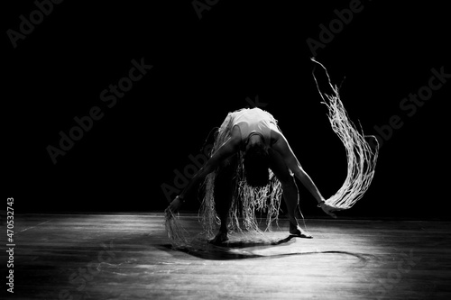 Contemporary dancer dancing in theater with black background and straw accessory. photo