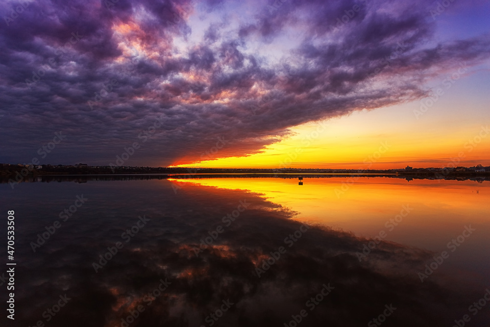 Beautiful sunset on the lake with clouds and reflections in the water