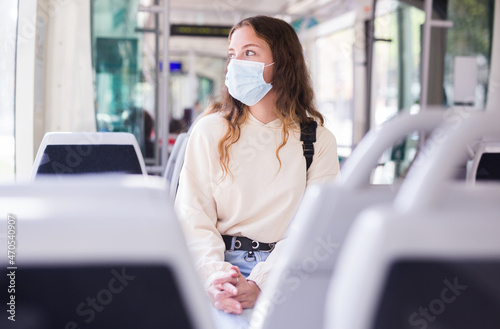 Portrait of stylish young female wearing surgical protective mask during her travel inside tram