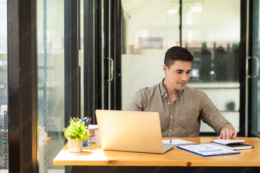 Businessman working with marketing graphs and laptop in online working concept with financial documents and analytical calculators while sitting in the office.