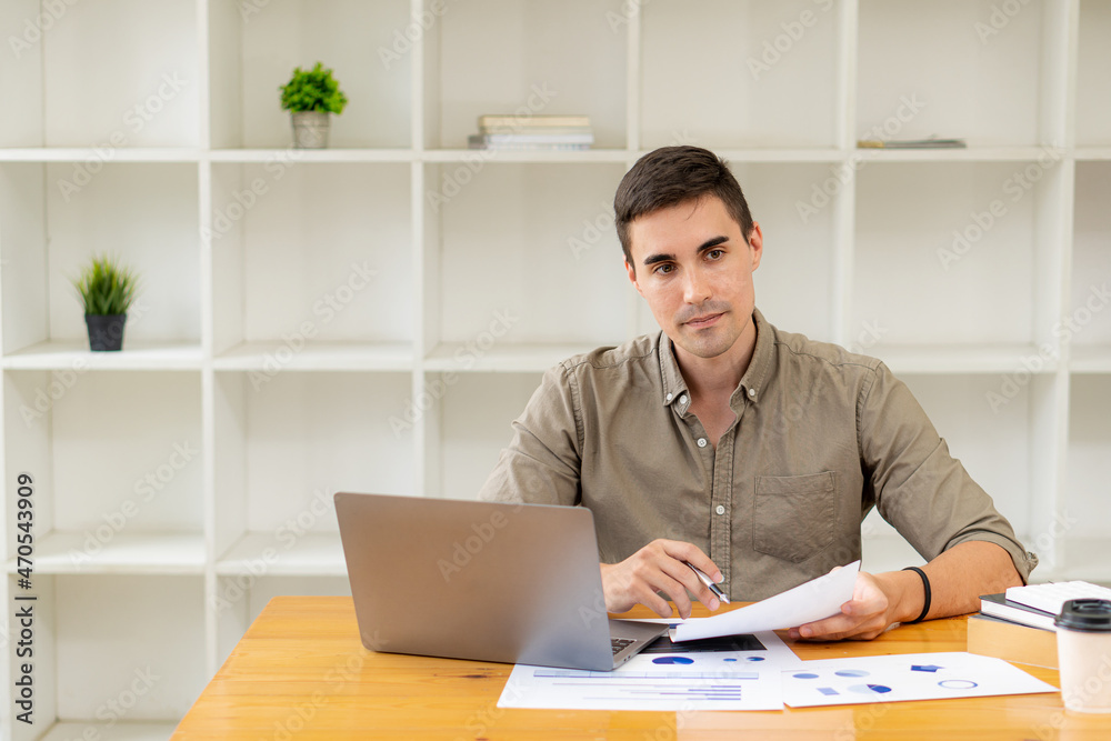 Businessman working with marketing graphs and laptop in online working concept with financial documents and analytical calculators while sitting in the office.