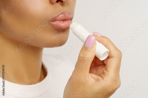 African woman applying balsam lipstick to moisturize lips and protect from cold and wind. Unrecognizable black female using natural hygienic balm for skin protection and skincare, closeup cropped shot