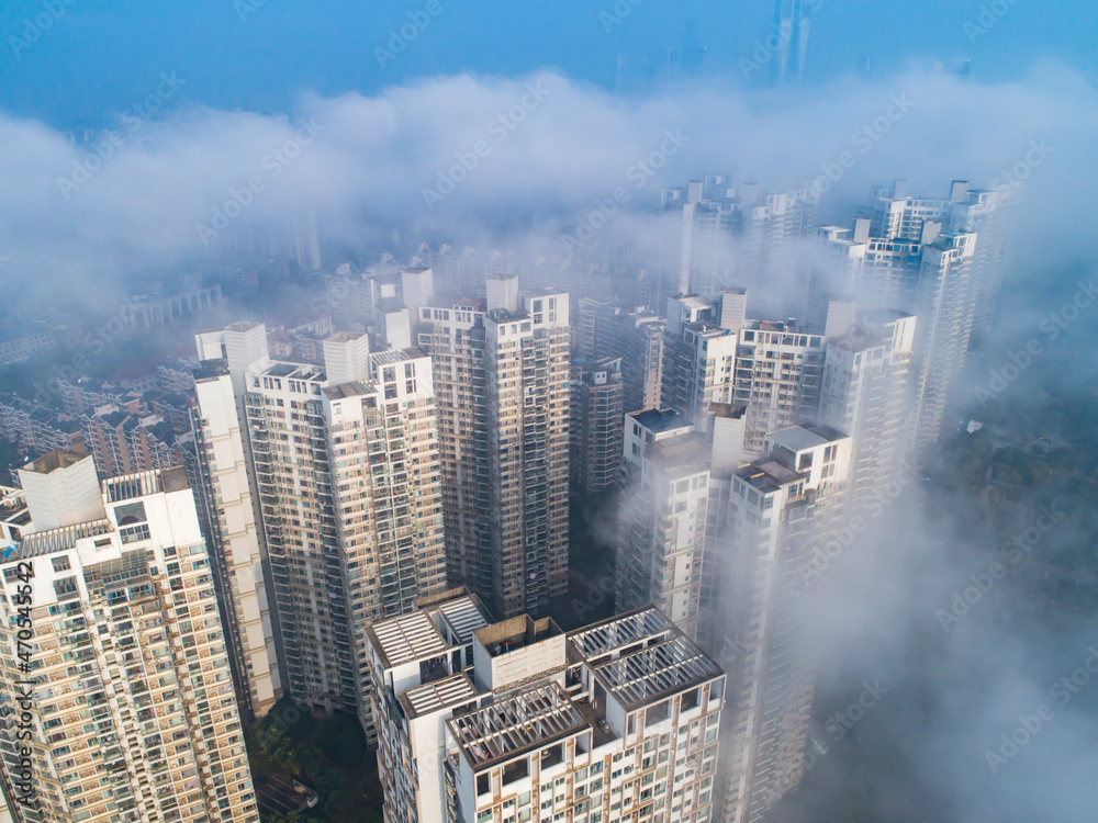 Heavy fog on the river and forest in calm morning weather. View of the residential buildings through the haze.morning urban landscape. Foggy City.Houses Protruding Through Fog.