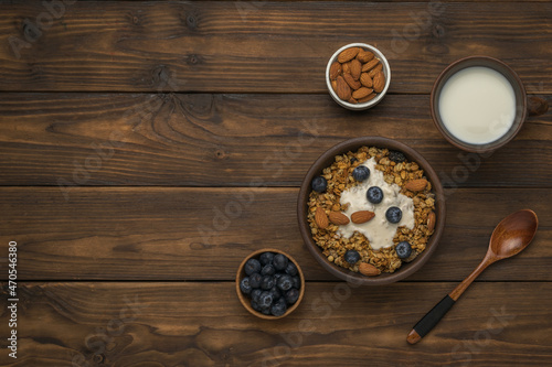 Breakfast of muesli, yogurt, berries and milk on a rustic table. Flat lay. Place for text.