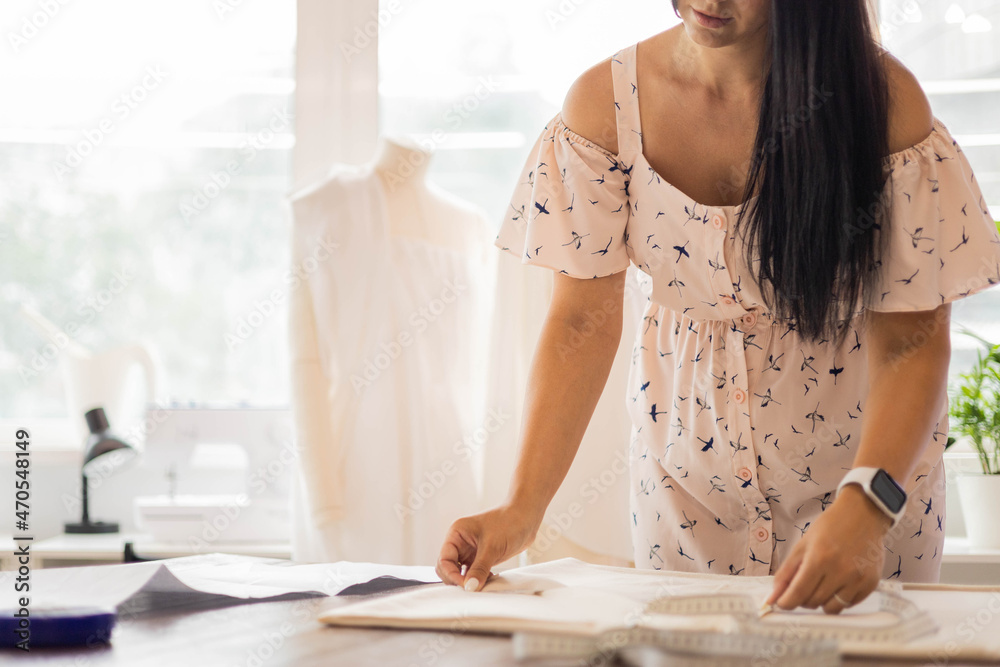 Happy dressmaker female use sewing patterns and measuring tape for creating fashion clothes Happy dressmaker female use sewing patterns and measuring tape for creating fashion clothes