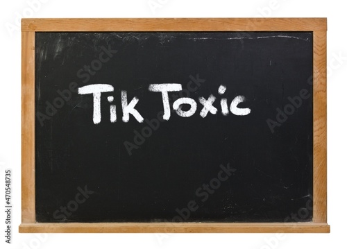 Tik Toxic written in white chalk on a black chalkboard isolated on white