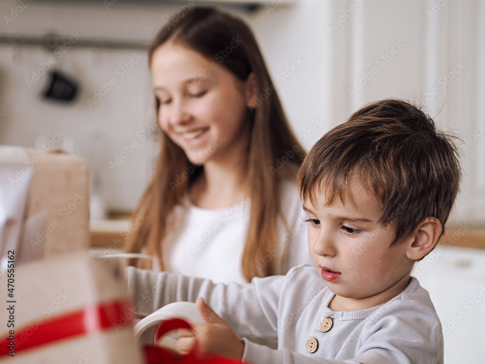 Cute cuacasian toddler boy no front teeth packing christmas boxes with sister not in focus Cute cuacasian toddler boy no front teeth packing christmas boxes with sister not in focus