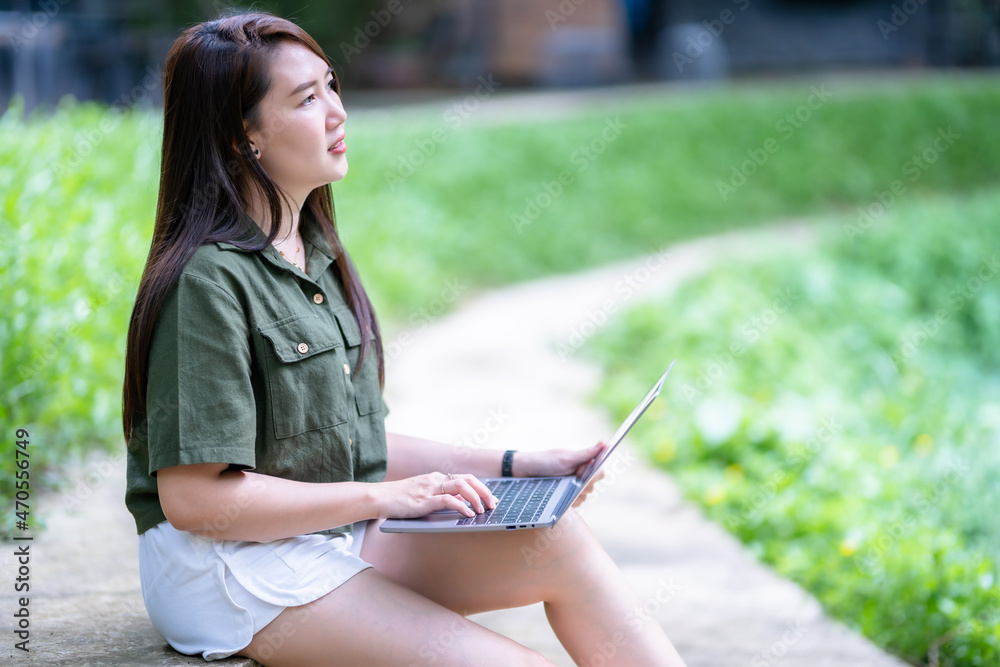 Obraz premium Happy of asian freelance people business female casual working with laptop computer outdoors at sunny summer day in park background,education and remote working communication concept