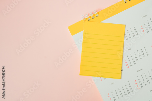 blank yellow note paper with line and yearly calendar on sweet pink background , top view, with copy space
