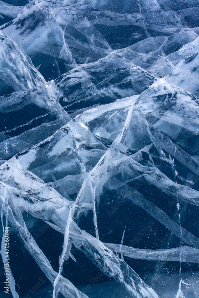 Natural ice with cracks. Blue thick ice with white cracks. Vertical. Natural ice with cracks. Blue thick ice with white cracks. Vertical.