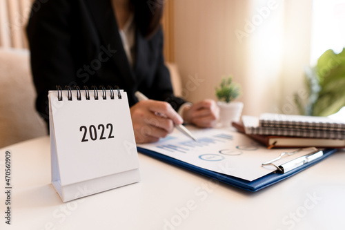 Desktop calendar 2022 with business Asian woman work on computer laptop in office.
