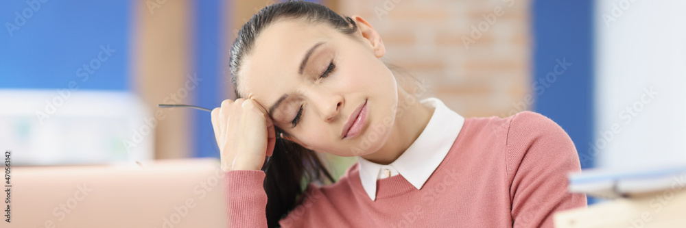 Tired young woman sits at workplace with closed eyes Tired young woman sits at workplace with closed eyes