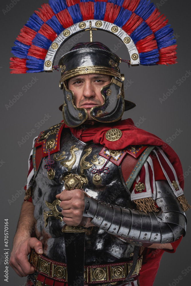 Roman legionary with sword posing against gray background