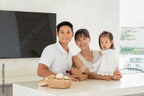 RETRATO DE UNA HERMOSA FAMILIA ORIENTAL EN LA COCINA DISFRUTANDO UNA DELICIOSA COMIDA Y VIENDO A CÁMARA photo