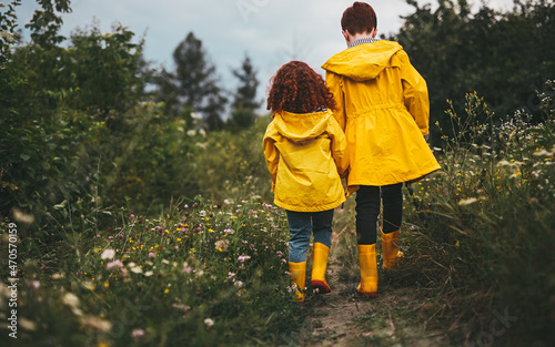 Schilderij op canvas Ginger siblings in yellow raincoats and runner boots in field