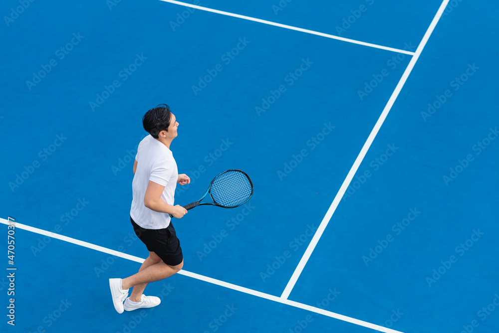 hombre asiático trotando camino a jugar tenis en una cancha de color azul