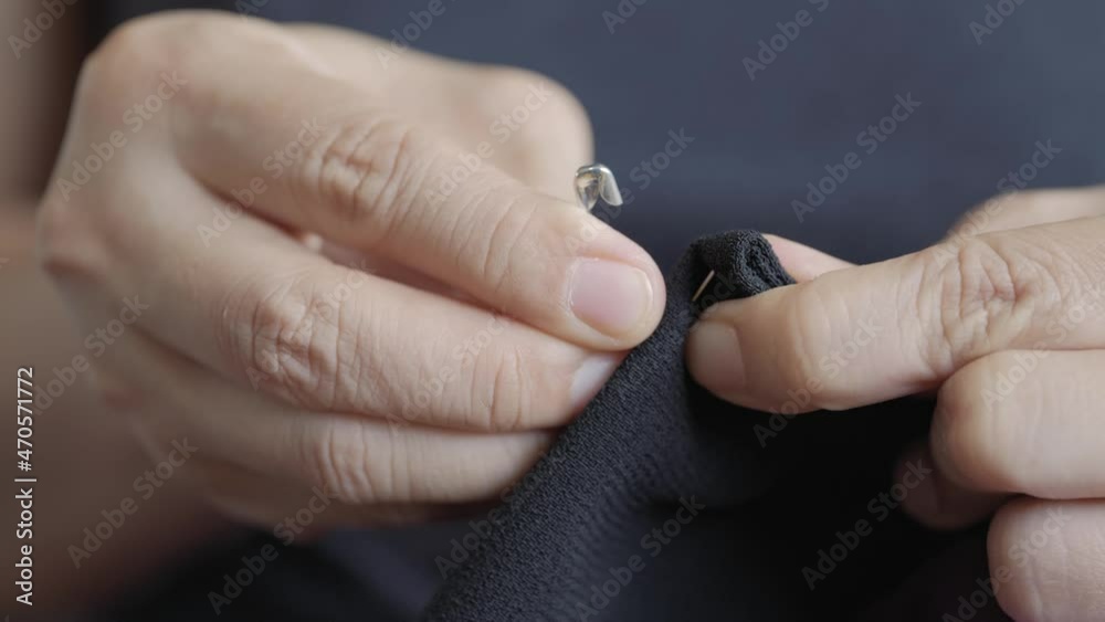 woman hands put safety needle pin on the cloth for sewing or pregnancy symbol use. woman hands put safety needle pin on the cloth for sewing or pregnancy symbol use.