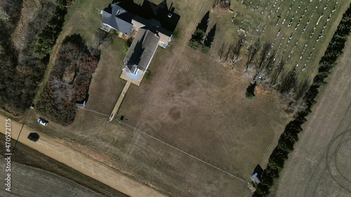 Top-down aerial view from high above showing black car driving along a dusty dirt road and passing St Boniface Church in Flagstaff County, Alberta. Slowly forward camera movement revealing cemetery. photo