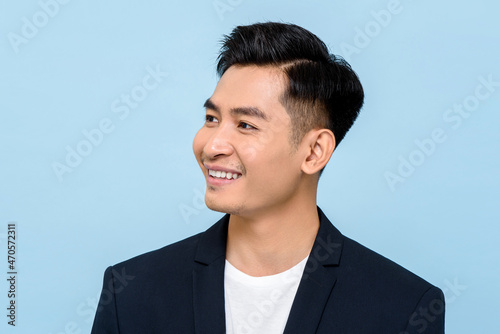 Young Asian man smiling and looking sideways in isolated light blue color background photo