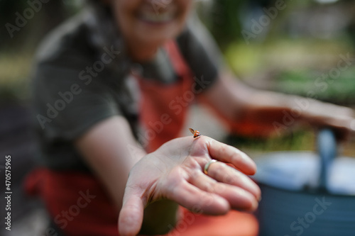 Unrecognizable woman holding ladybug in her hand outdoors in farm, close up.