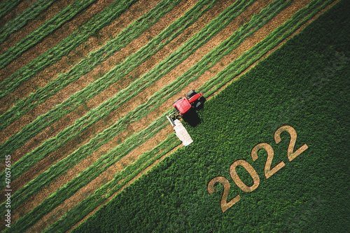Tela 2022 Happy New year concept and red tractor mowing green field