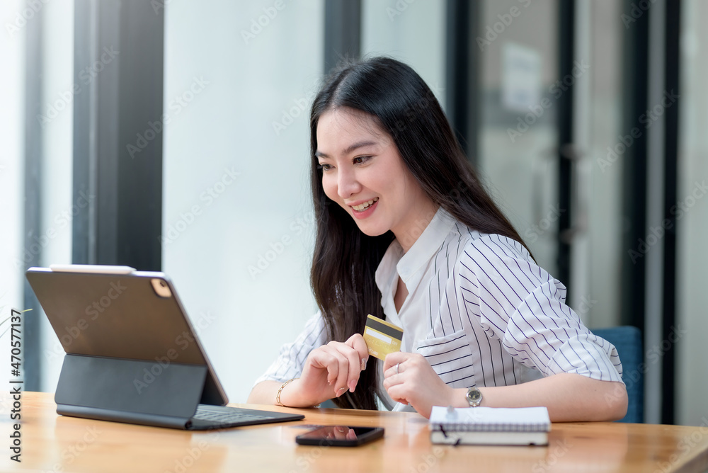 Pretty young Asian woman using tablet computer and using credit card for online shopping. Pretty young Asian woman using tablet computer and using credit card for online shopping.