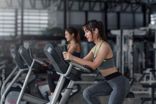 Young Asian woman working out on exercise bike at gym.