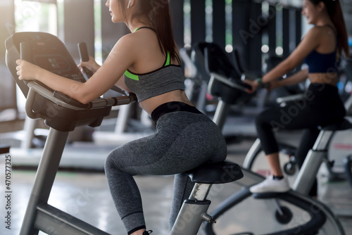 Young Asian woman working out on exercise bike at gym.