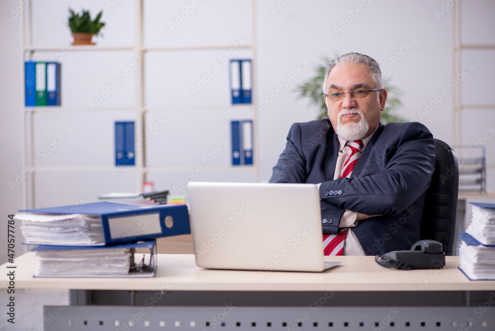 Old male employee sitting at workplace Old male employee sitting at workplace