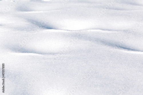 Snowy background of fluffy white snow shining in the sun. White natural background. Winter texture © Maryana