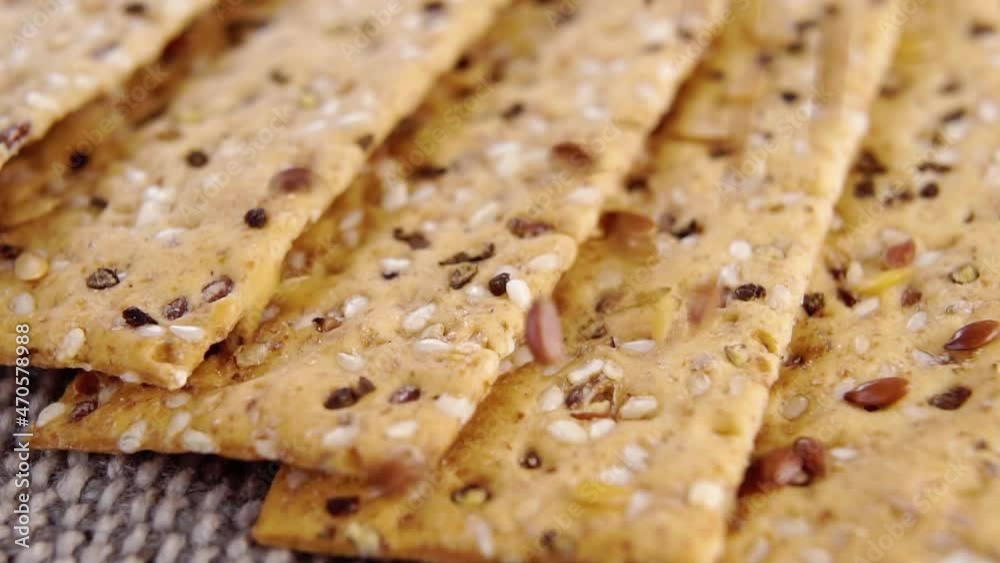Crunchy crispbreads with falling sesame and flax seeds. Healthy dietary food. Macro. Rotation. Dry bread slices on a rough rustic jute cloth. Whole grains. Slow motion Crunchy crispbreads with falling sesame and flax seeds. Healthy dietary food. Macro. Rotation. Dry bread slices on a rough rustic jute cloth. Whole grains. Slow motion