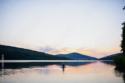 Fototapeta Naklejka Na Ścianę i Meble -  Rear view of active senior woman swimmer diving outdoors in lake, panoramic scene with sunset