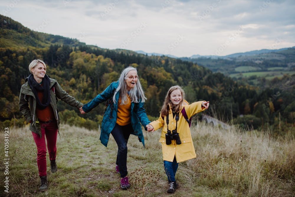 Small girl with mother and grandmother hiking outoors in nature.