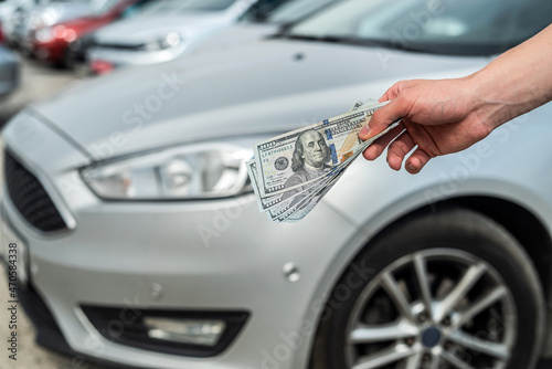 man holding dollars for buying new modern car © RomanR