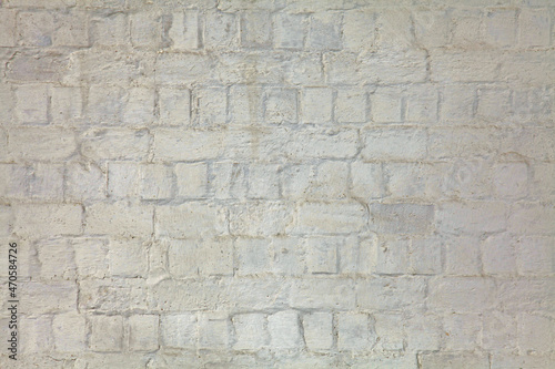 White and uneven whitewashed wall, texture, background. Ancient building wall, painted with whiting. Wavy, bumpy bricky surface. Dilapidated and crumbling surface, faded with age