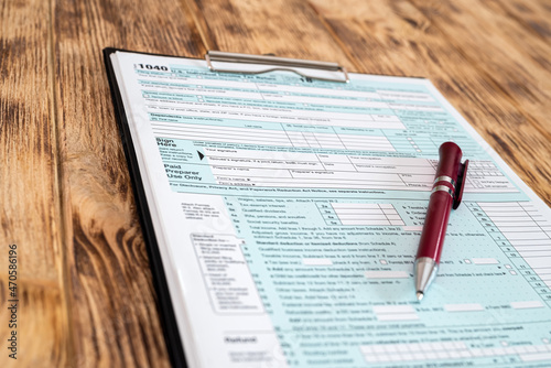 high-quality US tax form 1040 is placed on a tablet and a red pen is on the table