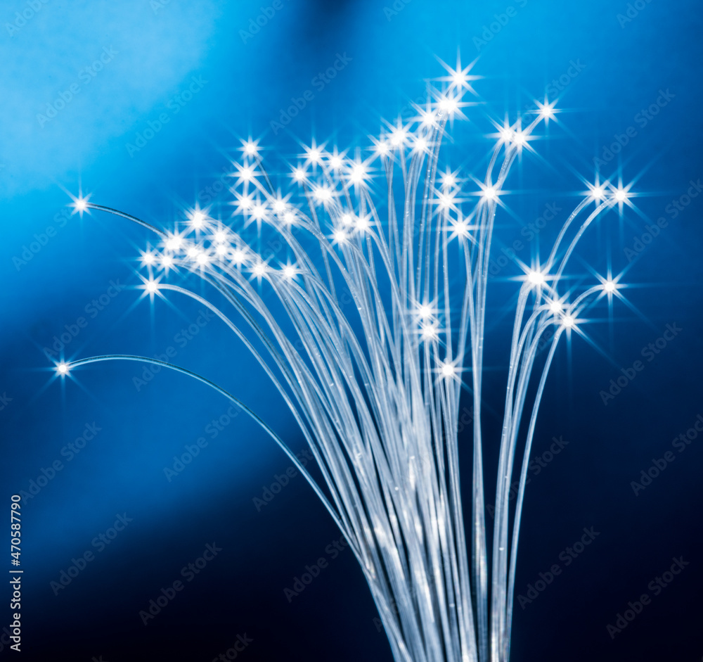 Fototapeta premium Bundle of optical fibers with lights in the ends. Blue background.
