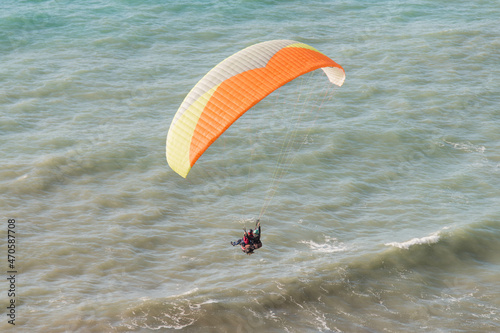 tandem paraglider flies against the background of the blue sea.