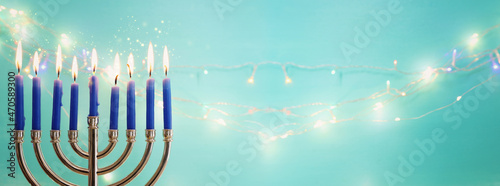 Image of jewish holiday Hanukkah with menorah  traditional candelabra  and candles over garland glitter lights background