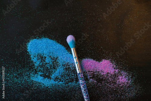 Makeup brush and shiny pink and blue sequins on a black background. Festive magic makeup concept. Template for design, top view Flat Lay Copy space.