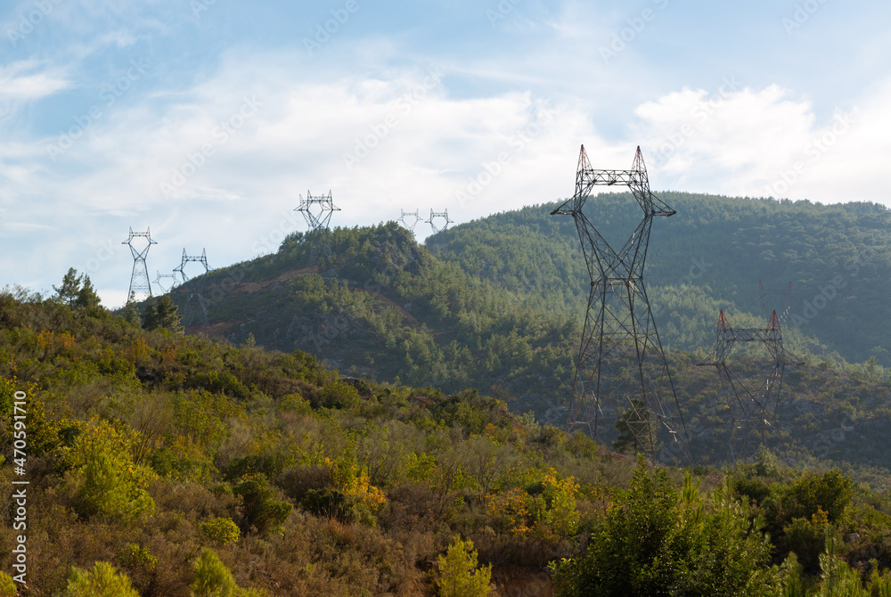 Fototapeta premium High voltage electricity poles installed on opposite slopes of a deep valley. High voltage poles with high voltage wires not yet connected.