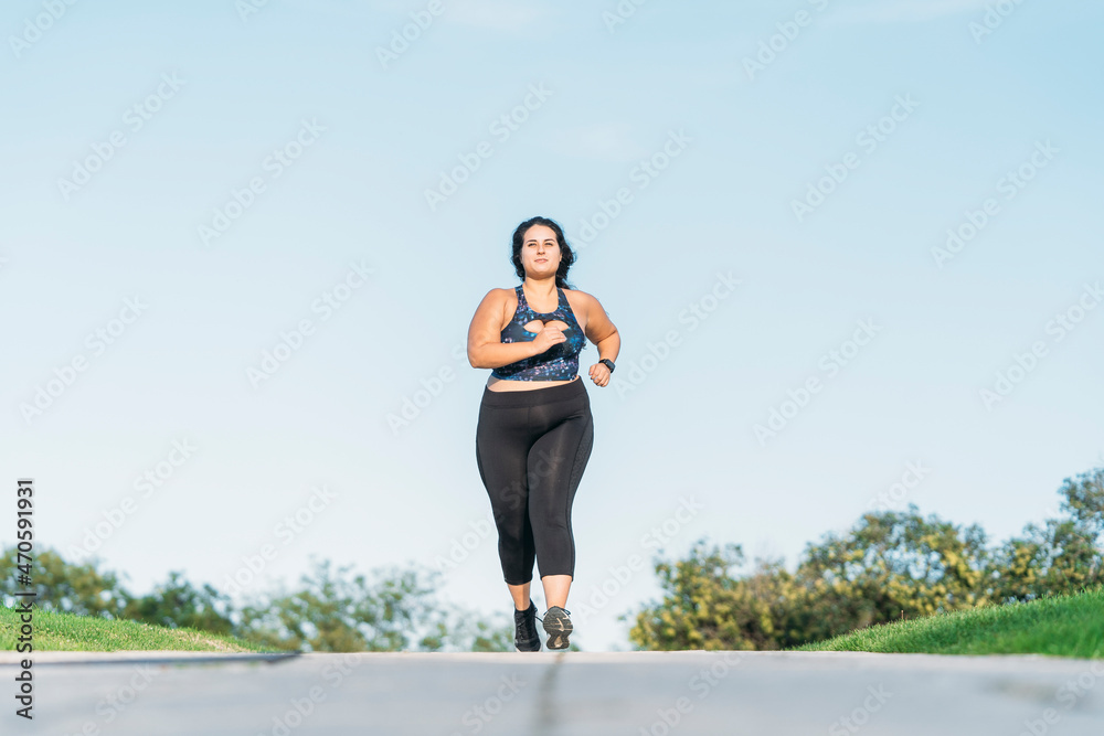 Plus size sportswoman running on road Plus size sportswoman running on road
