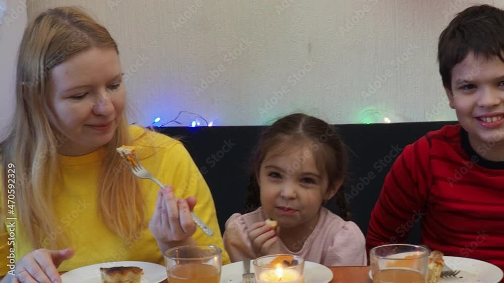 happy mother son and daughter embracing at thanksgiving holiday table, celebrate thanksgiving, eat pumpkin pie, sit at the table, drink drinks.